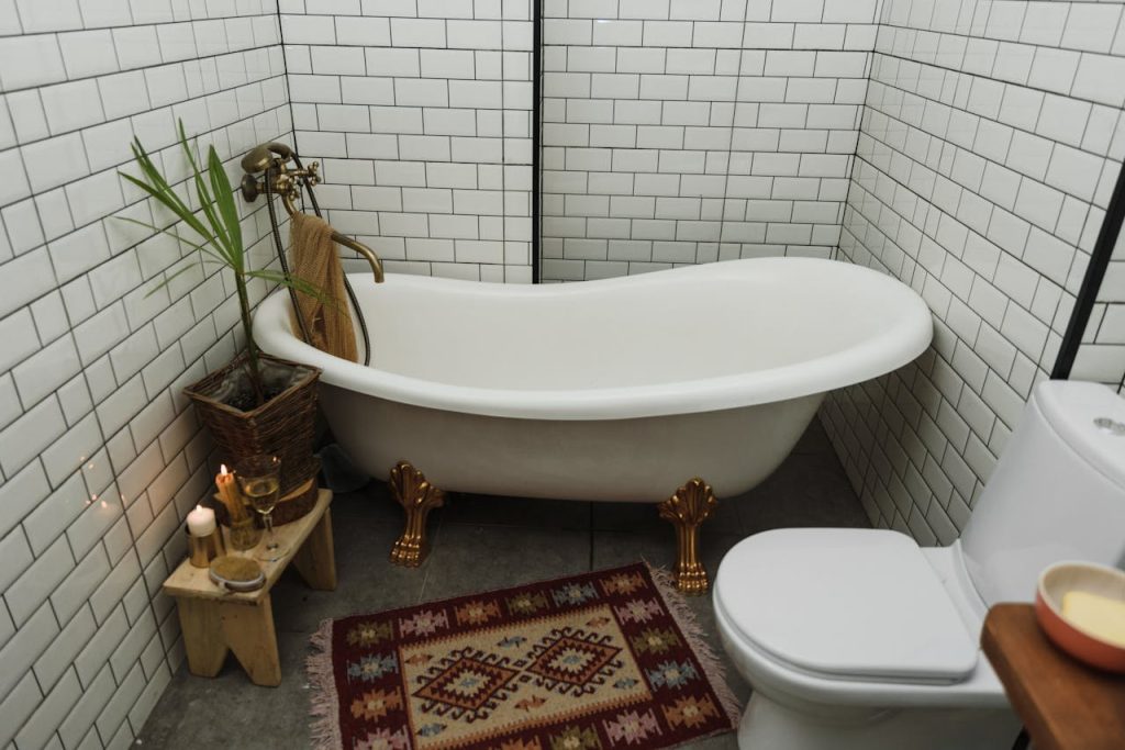 Cozy bathroom featuring a vintage-style clawfoot bathtub, white tiles, and a patterned rug for a warm interior design.
